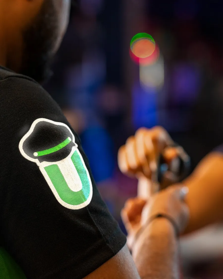 Close on the reflective DriveU badge on a driver&rsquo;s sleeve as a customer hands over her car keys