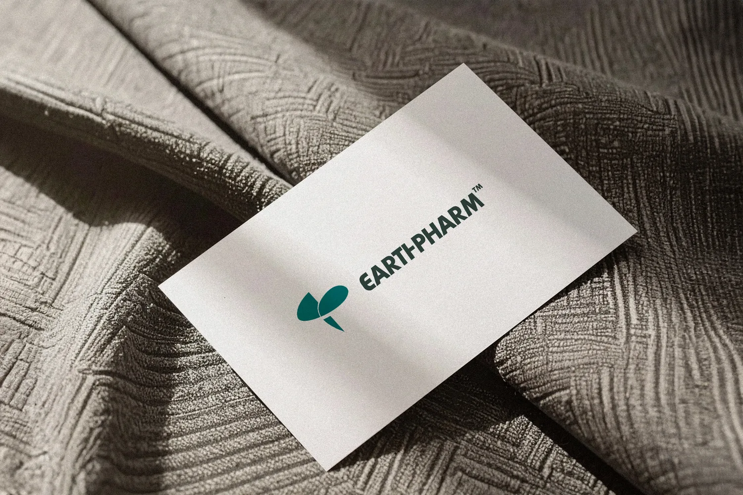 A business card with the secondary logo, on a textured cloth, as designed